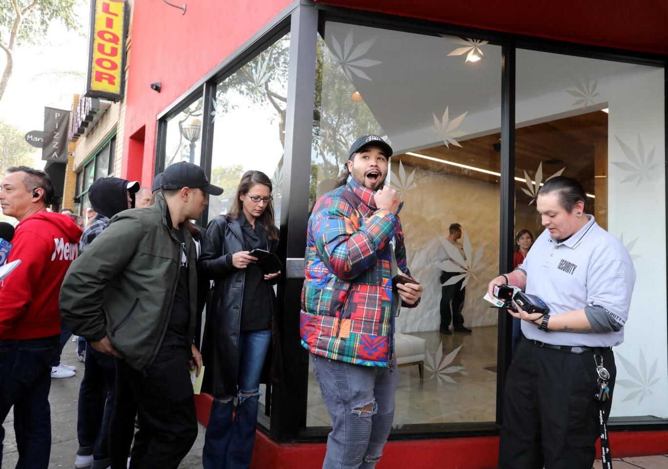 Josh De La Cruz (c) reacciona después de haber escaneado su licencia de conducir para ser la primera persona autorizada en el dispensario MedMen para comprar productos de marihuana recreativa en West Hollywood, California.