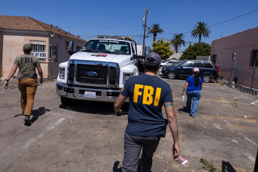 Van Nuys, CA - August 28: Federal investigators work to seize vehicles at Baba Cars on Wednesday, Aug. 28, 2024 in Van Nuys, CA. (Brian van der Brug / Los Angeles Times)