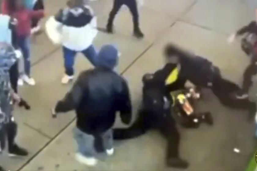 This image taken from video provided by the New York City Police Department shows police officers confronting a group near New York's Times Square, Jan. 27, 2024, bringing a man in a bright yellow coat down to the sidewalk and the chaotic scene that unfolds as at least half a dozen bystanders are seen kicking at the officers, then trying to pry them off the man. (New York City Police Department via AP)