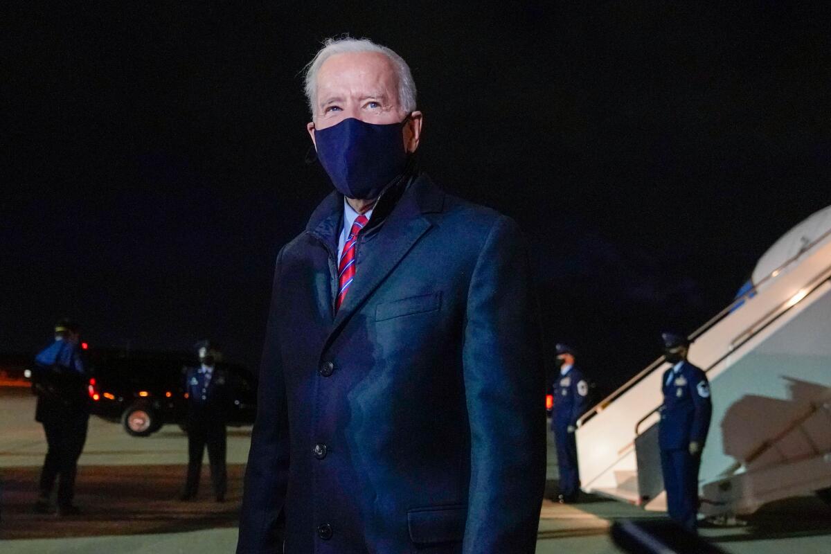 President Biden on a tarmac with Air Force One behind him at night.