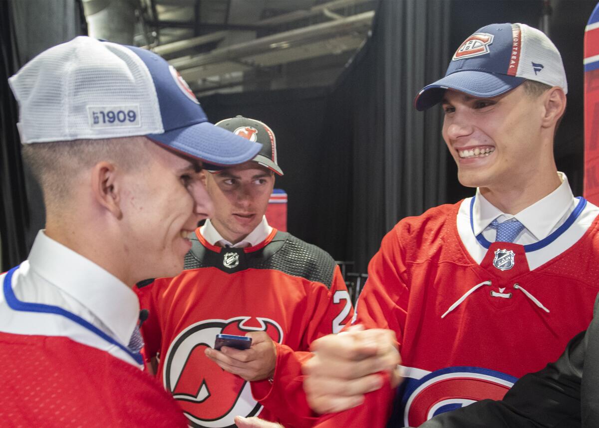 Juraj Slafkovsky, right, of Slovakia, greets countryman and fellow Montreal Canadiens draft pick Filip Mesar, left, as Simon Nemec, also from Slovakia and a New Jersey Devils pick, looks on during the first round of the NHL hockey draft in Montreal on Thursday, July 7, 2022. (Graham Hughes/The Canadian Press via AP)