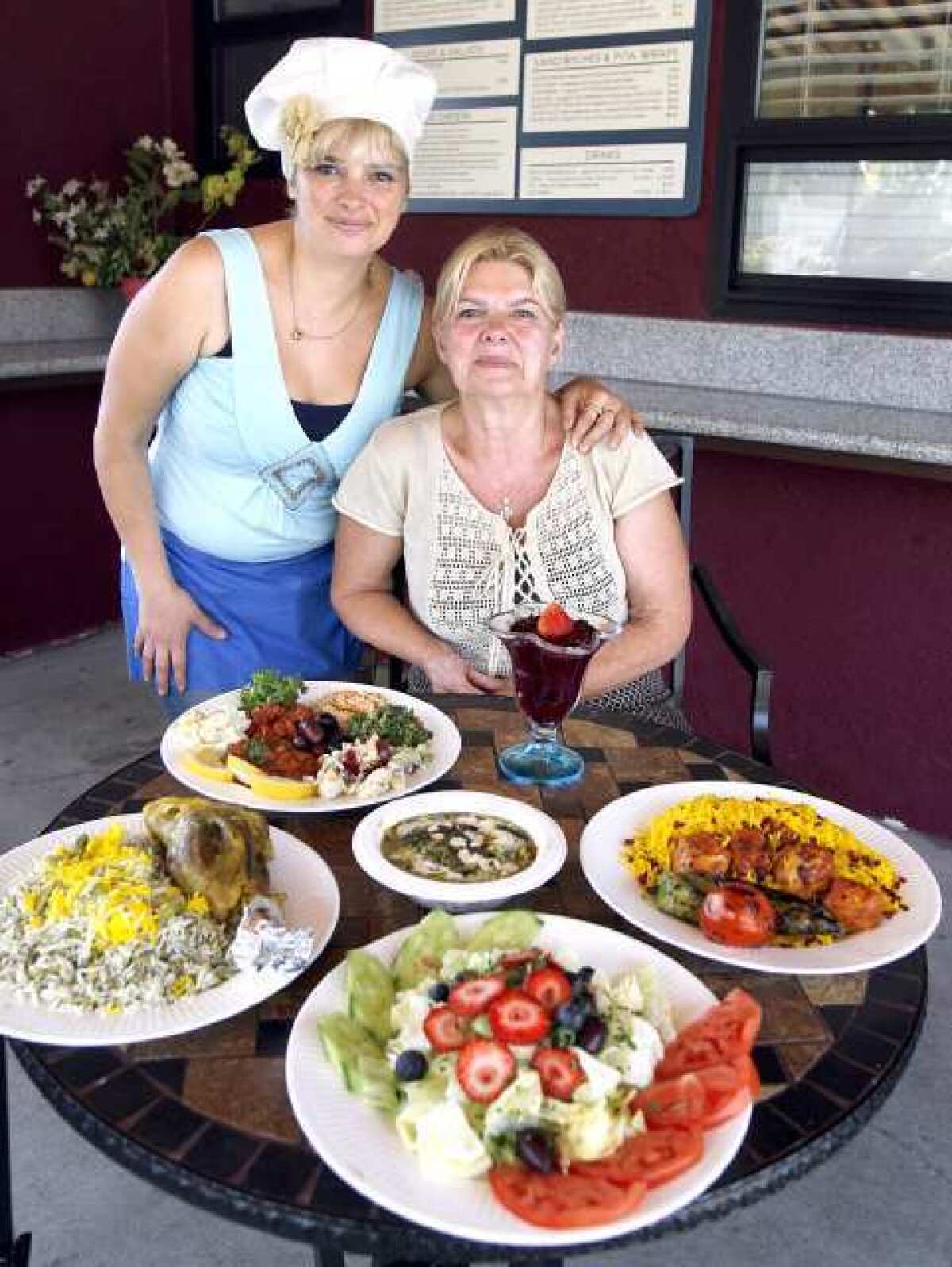 Owners Sonia Race, left, and her mother Zina Race, at Zina's Healthy Corner in La Canada Flintridge. Clockwise from left are lamb shank with fava bean rice, a selection of sides, boneless chicken breast kabob and a salad with fruit.