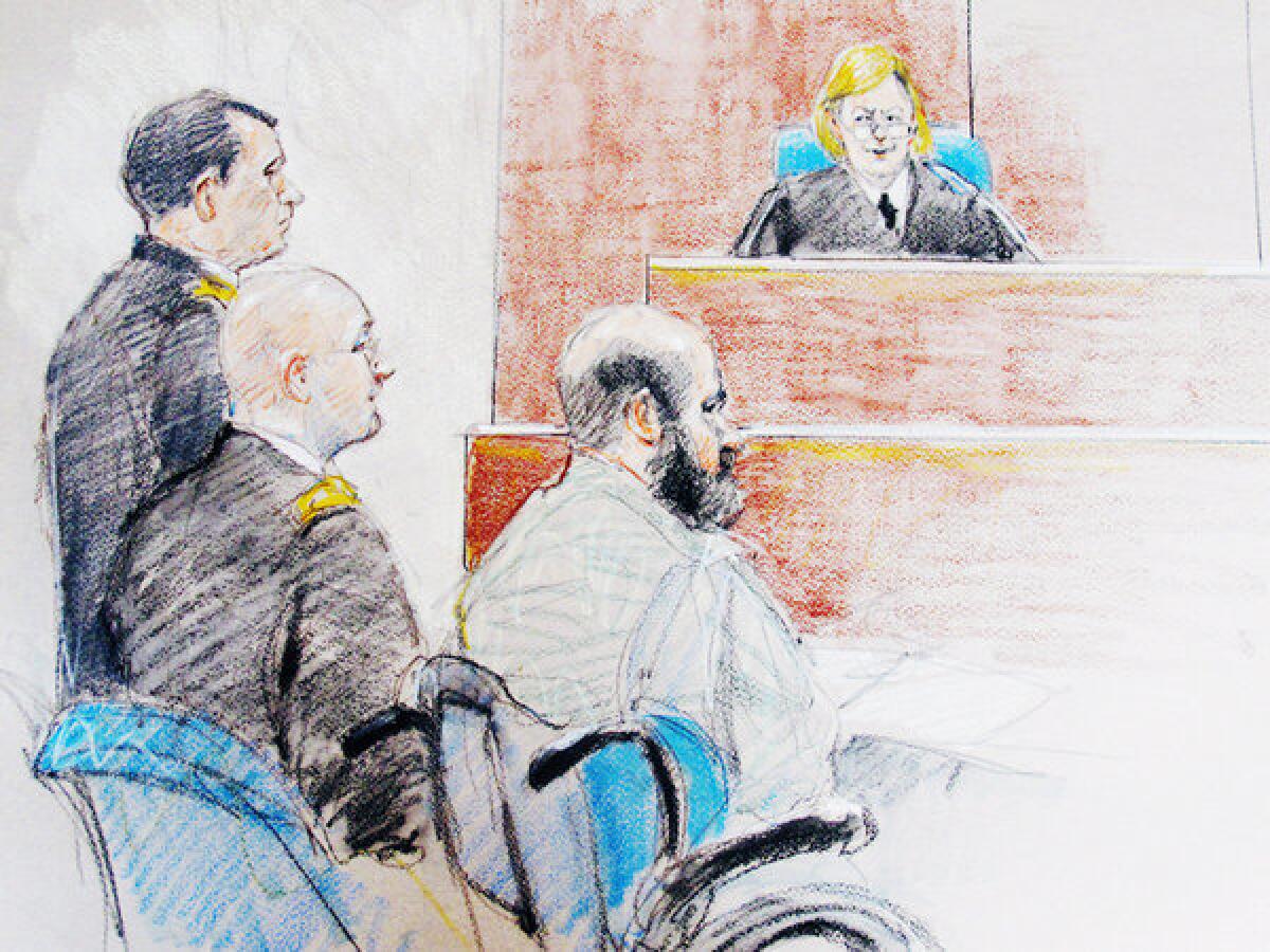 In this file courtroom sketch, Nidal Malik Hasan, right, is seen sitting by his former defense attorneys during a hearing at Fort Hood, Texas. The judge, Col. Tara Osborn, has said the long-delayed trial into the mass shooting at the base will begin next month.