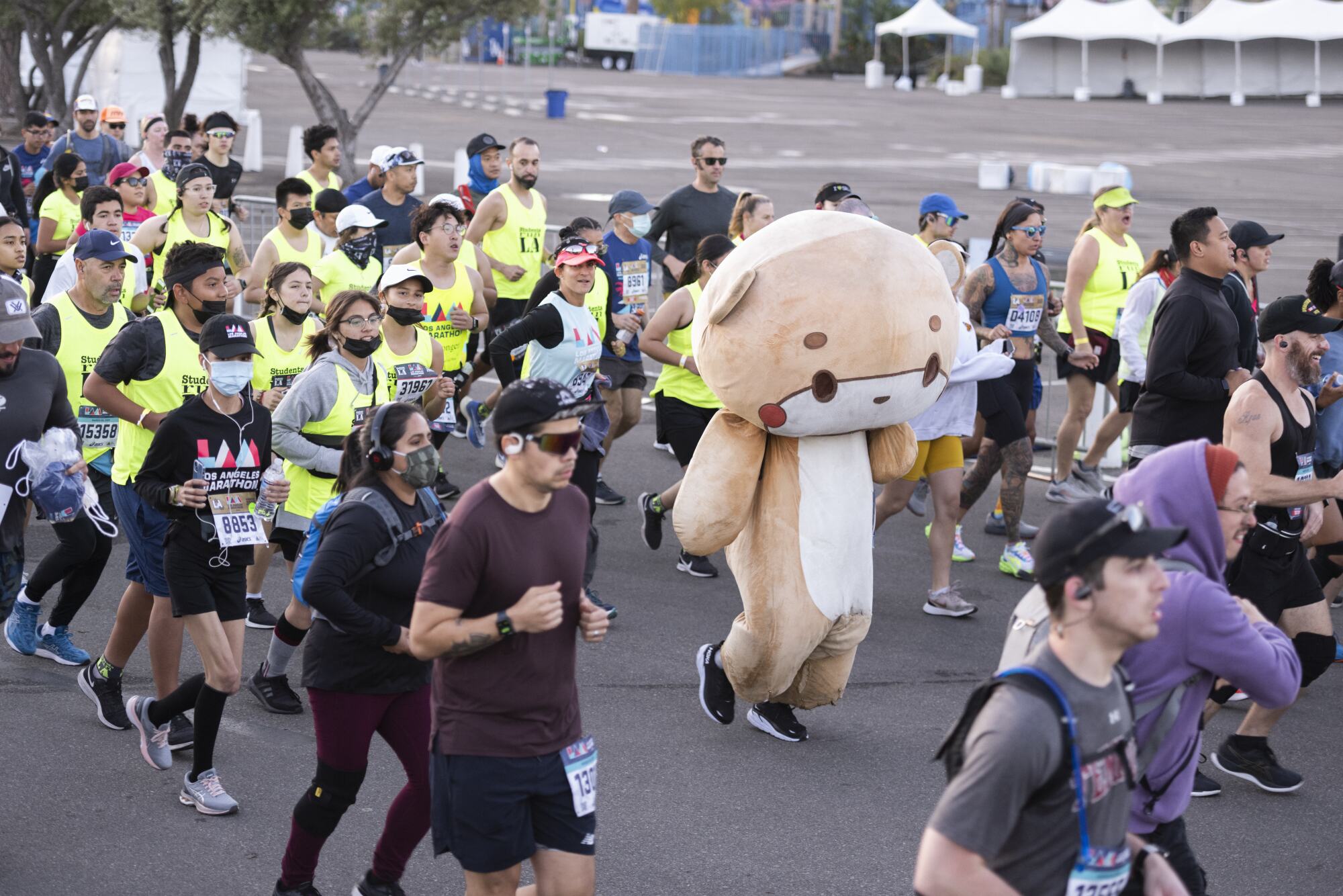 A runner in an animated bear costume participates in the Los Angeles Marathon alongside other runners.