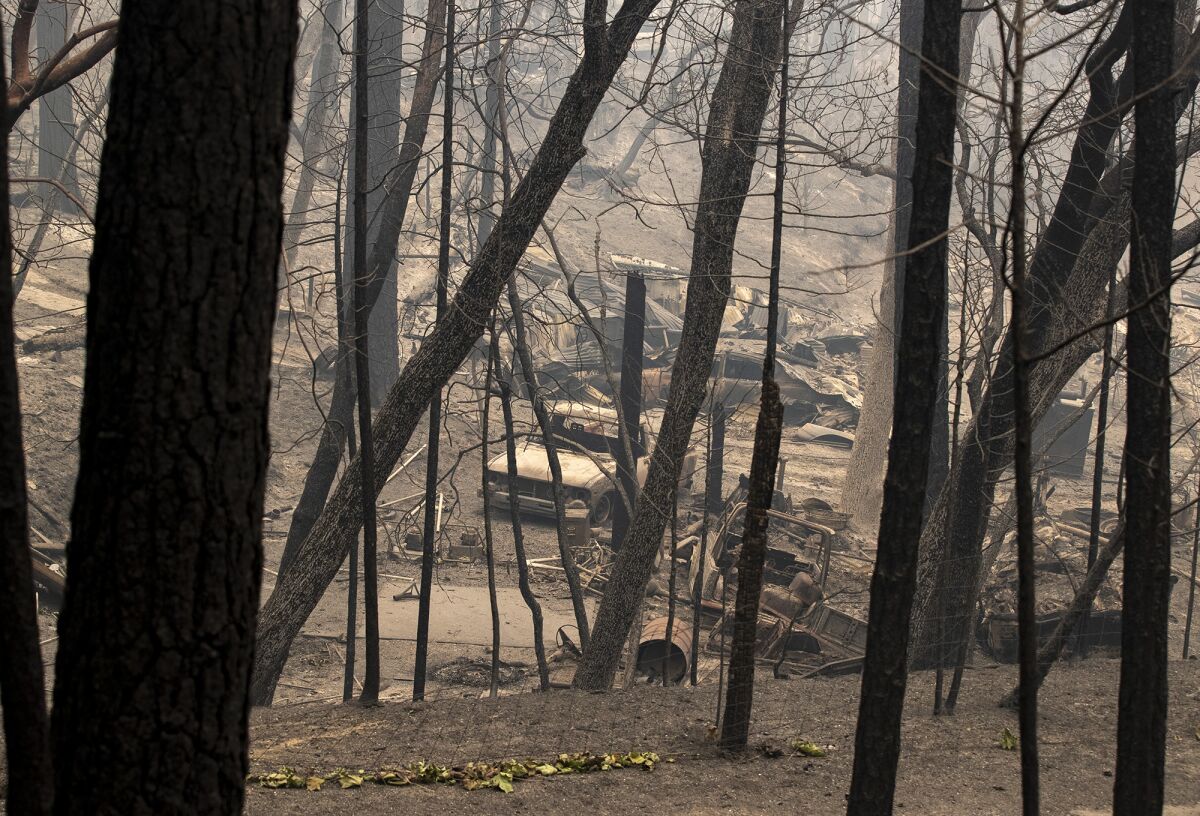 Burned vehicles sit Friday in front of a home destroyed in the North Complex fire.