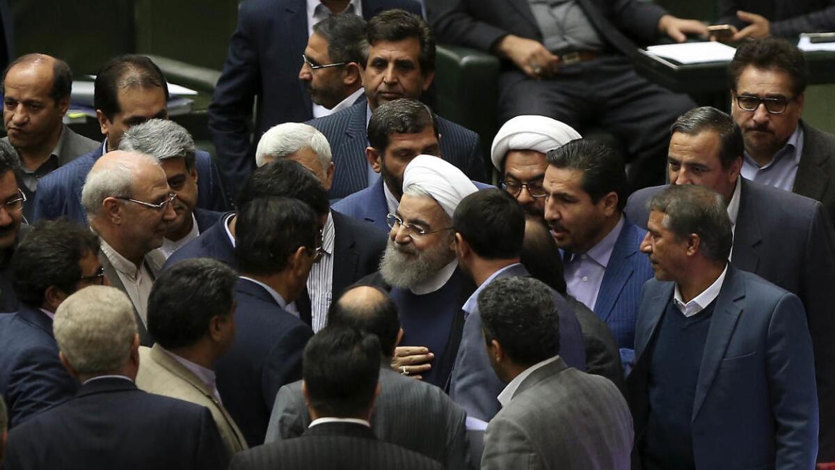Iranian President Hassan Rouhani is surrounded by lawmakers in parliament Sunday.