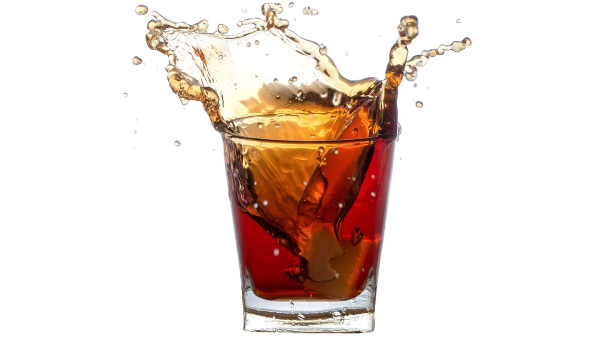 Splashing in a glass with soda from falling ice cubes isolated on a white background.