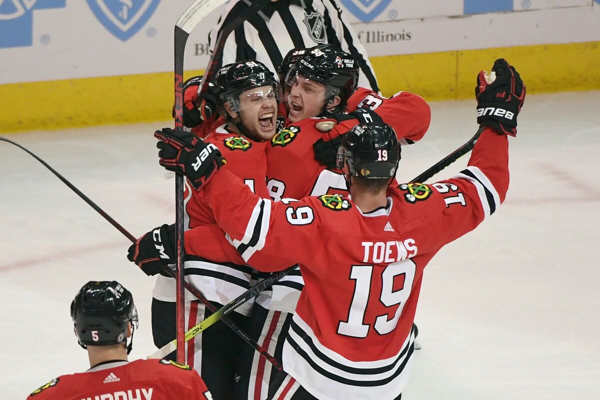 Chicago Blackhawks defenseman Riley Stillman, left, celebrates with right wing MacKenzie Entwistle, center, left wing Brandon Hagel, back, and center Jonathan Toews (19), after Entwistle scored during the second period of an NHL hockey game against the Washington Capitals, Wednesday, Dec. 15, 2021, in Chicago. (AP Photo/Matt Marton)