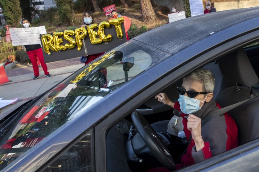 LINCOLN HEIGHTS, CA - DECEMBER 02: Nurse Helena Harvilicz, right, dances in her car to Aretha Franklin's "Respect" at Keck Hospital of USC where nurses are protesting unsafe working conditions at the hospital Wednesday, Dec. 2, 2020 in Lincoln Heights, CA. (Brian van der Brug / Los Angeles Times)
