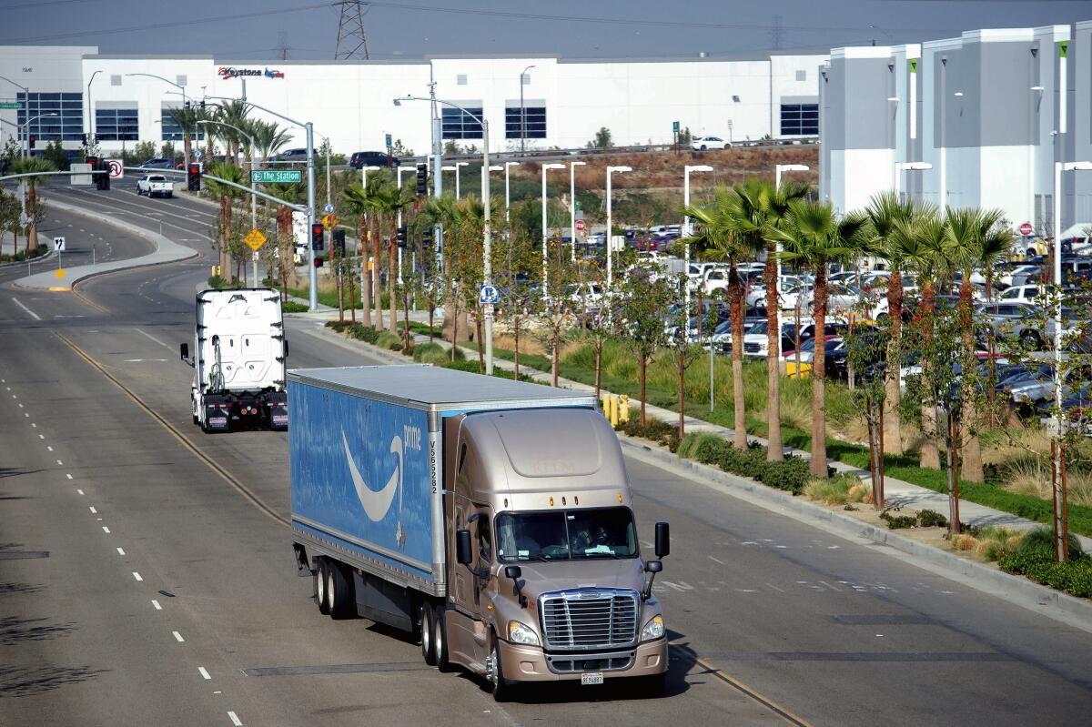 FILE - A semi-truck turns into an Amazon Fulfillment center in Eastvale, Calif. on Thursday, Nov. 12, 2020. Online retail behemoth Amazon has agreed in a court settlement to comply with a California law that requires swift notice to warehouse workers of new coronavirus cases, the state's attorney general said Monday, Nov. 15, 2021. (Watchara Phomicinda/The Orange County Register via AP,File)