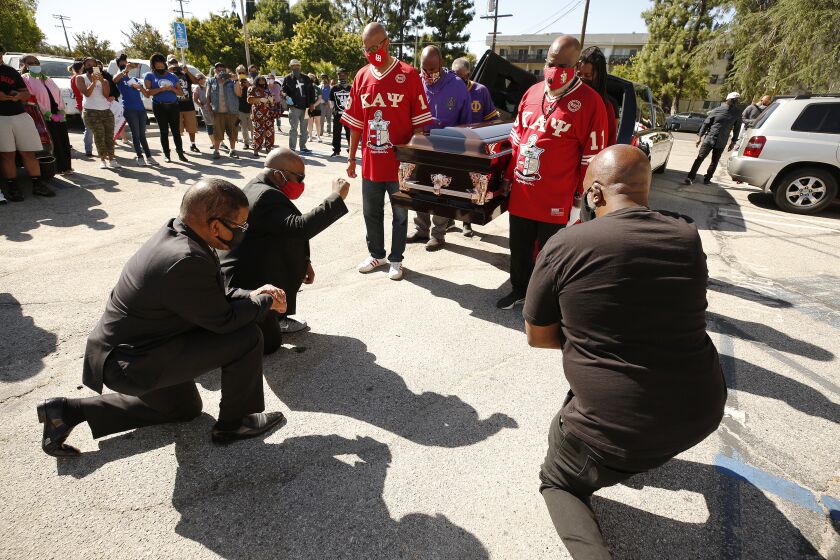 LOS ANGELES, CA - JUNE 08: Pastors Dewayne Winrow and James Thomas, left to right, of Reseda Church of Christ and Fluke Fluker, right, co-founder and president of Village Nation kneel as pall bearers carry a empty casket in memory of George Floyd at the Reseda Church of Christ, one of four starting points for vehicle processions by interfaith leaders, labor, people of color, immigrants, community members, and victims of police brutality as Black Lives Matter-LA is set to hold a memorial service in Downtown Los Angeles on Monday, June 8, honoring George Floyd and demanding justice for those killed by the hands of the police. Reseda on Monday, June 8, 2020 in Los Angeles, CA. (Al Seib / Los Angeles Times)