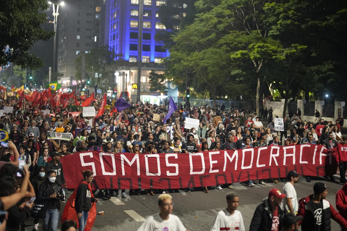 Manifestantes marchan con una bandera que dice "Somos democracia" durante una protesta