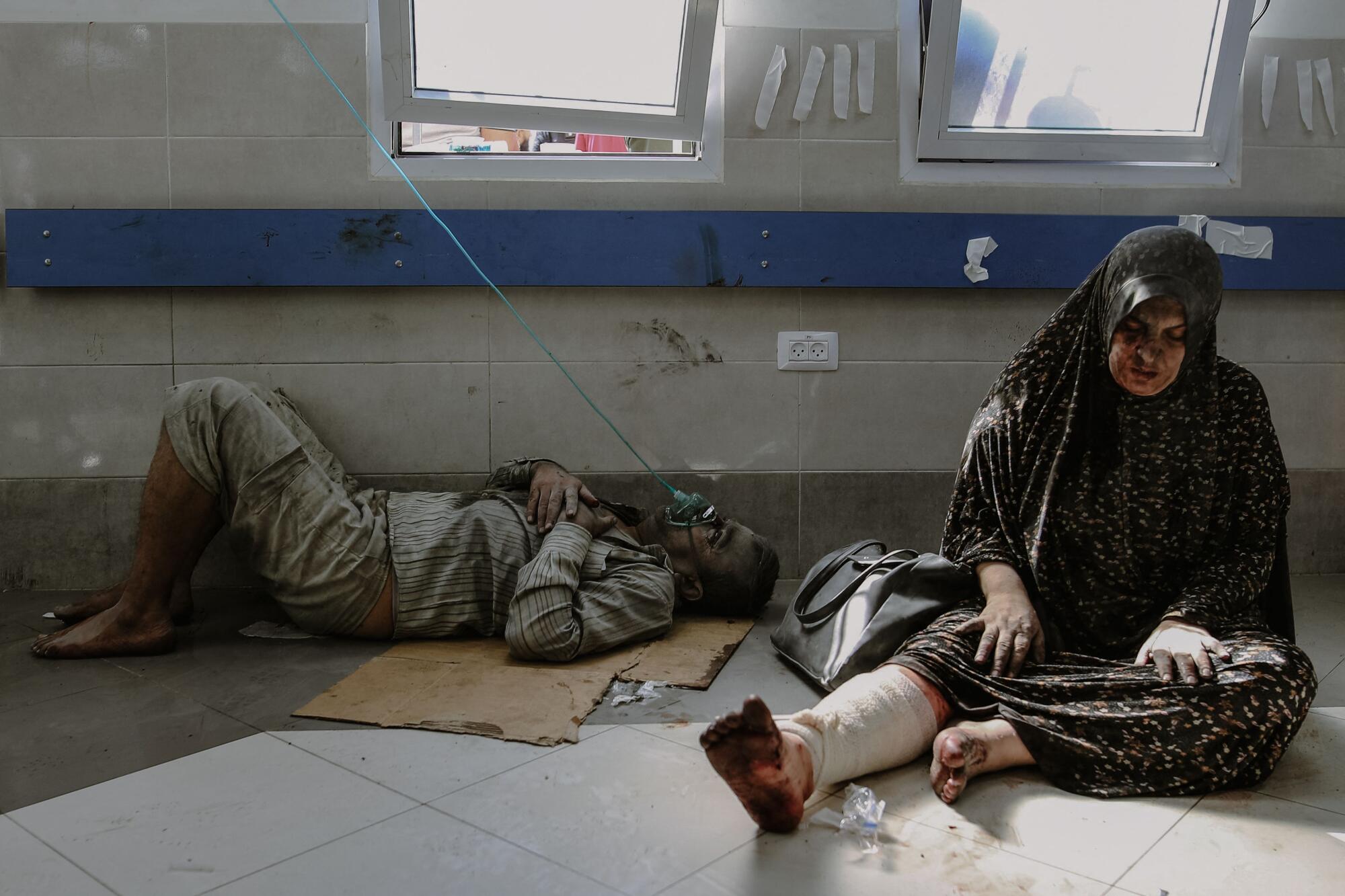 People sit on the floor as they wait for medical attention at Shifa Hospital in Gaza City. 
