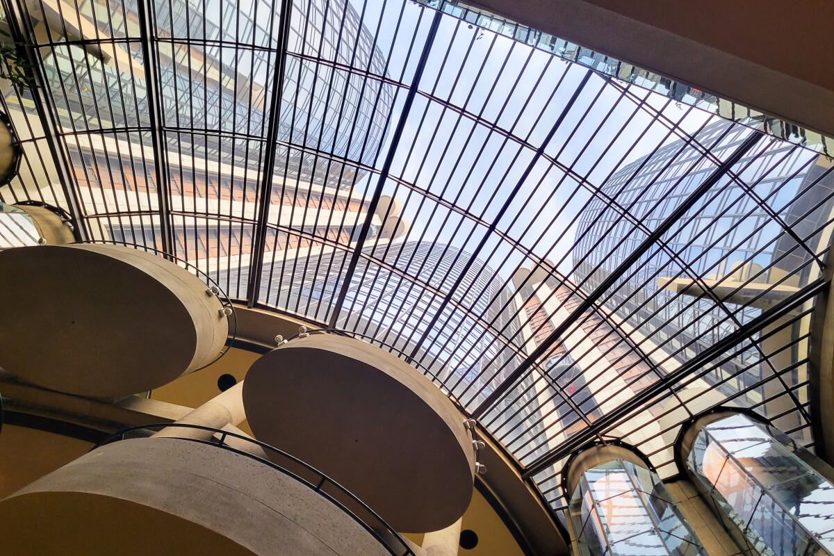 Through a vast curved skylight a hotel's round towers are visible.