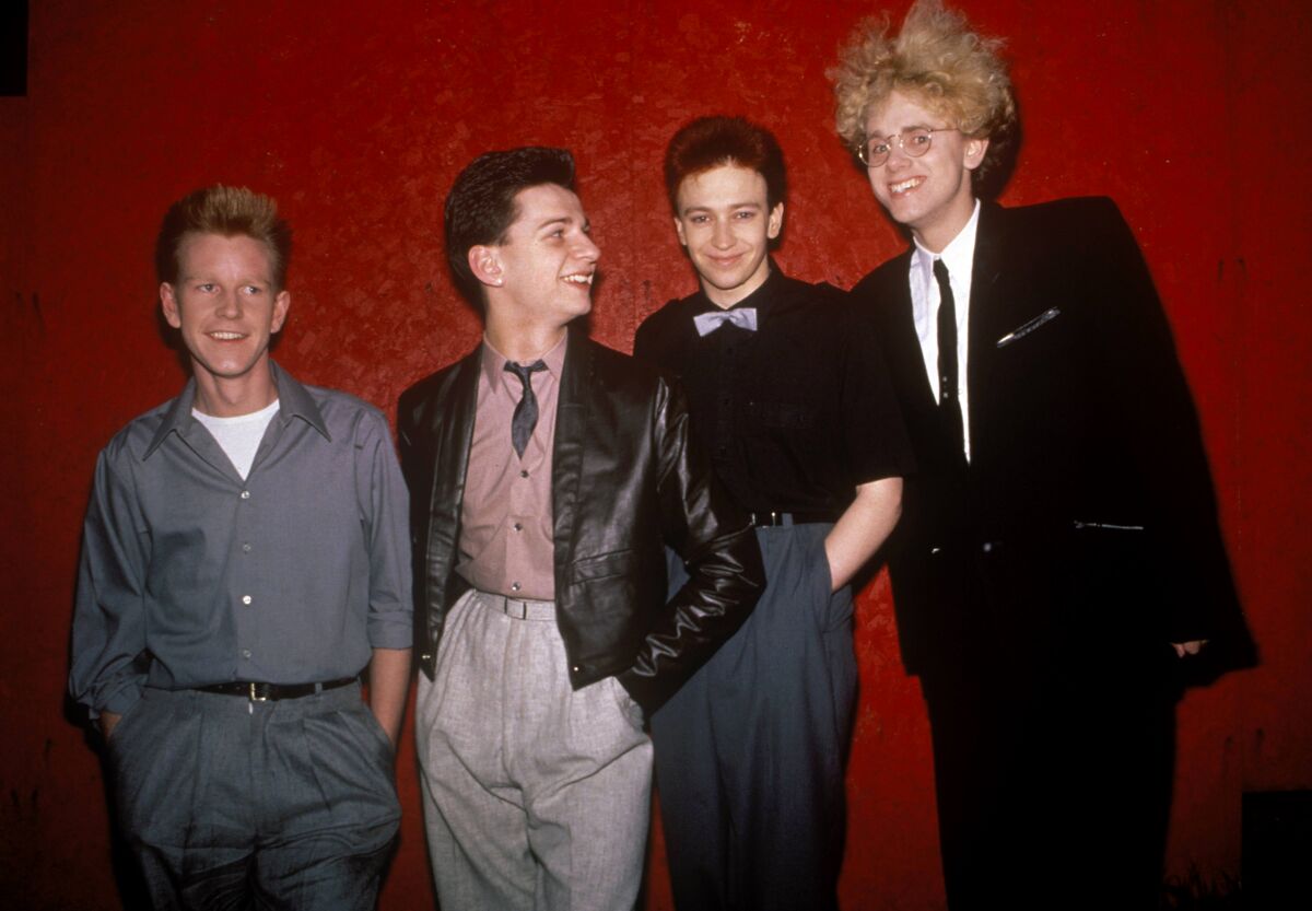 Four young men in 1980s outfits.