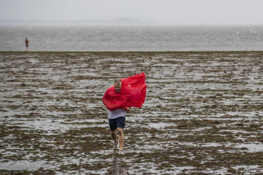 Curious sightseers walk in the receding waters of Tampa Bay due to the low tide and tremendous winds from Hurricane Ian in Tampa Tampa, Fla., Wednesday, Sept. 28, 2022. (Willie J. Allen Jr./Orlando Sentinel via AP)