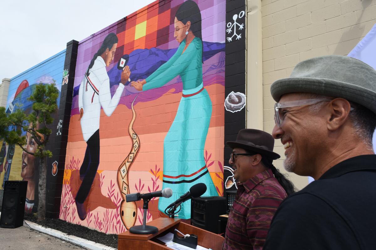 Artists Hector Villegas, center, and Gabriel Romo reveal a mural on June, 3, 2022, at MAAC Community Charter School. 