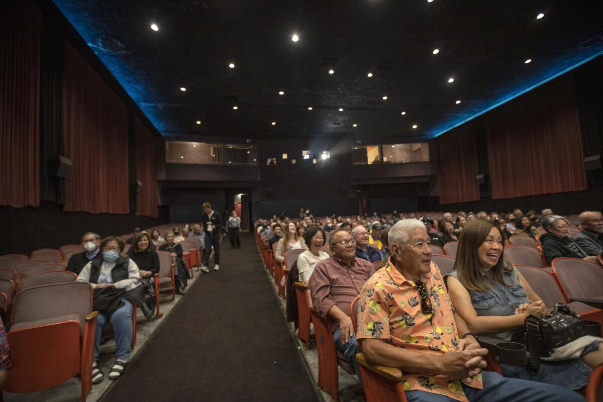 People sit inside a movie theater waiting for a film to start.