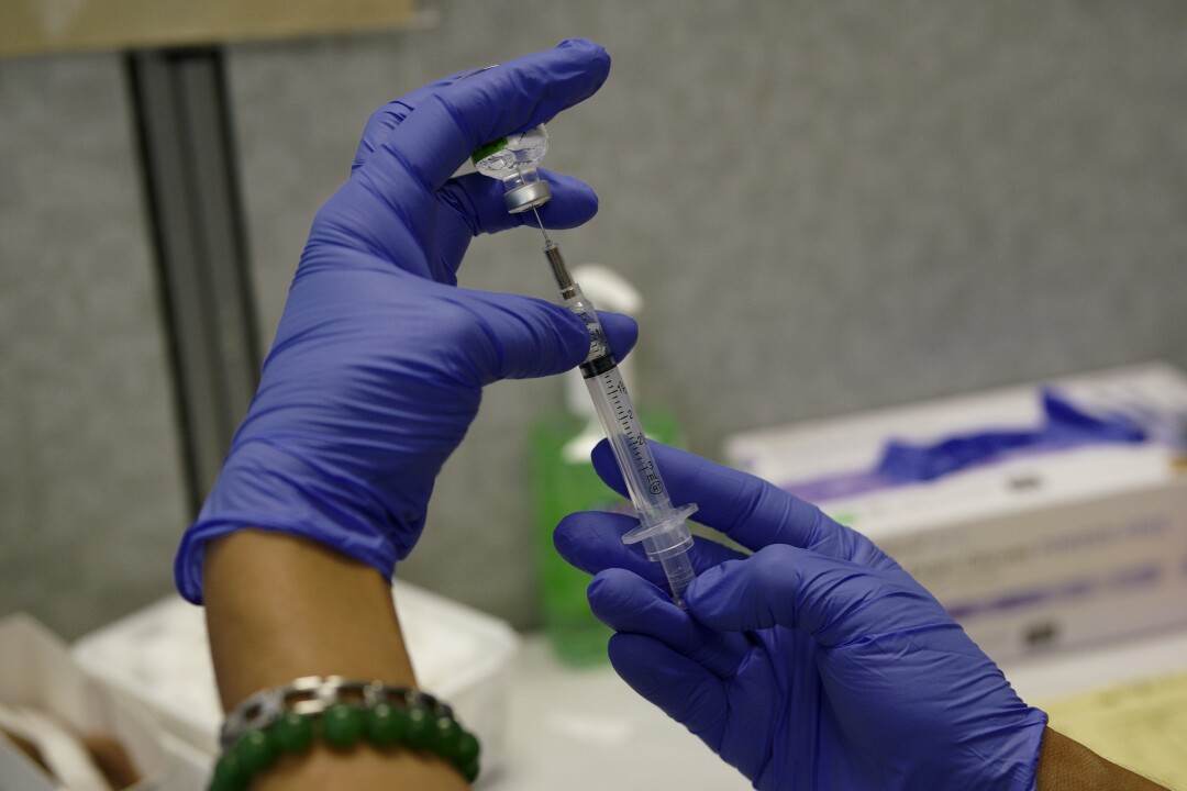 Медсестра округа Кармен Гомес готовит шприц для прививки от гриппа.