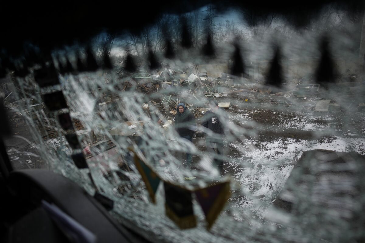 Men are seen through a smashed window of a damaged truck following a rocket attack in Kyiv.
