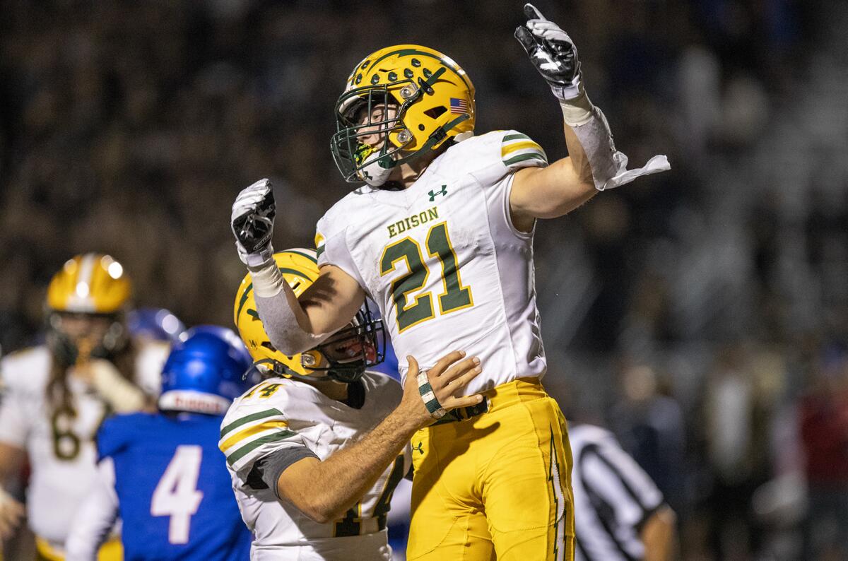 Edison's Parker Awad, left, lifts Troy Fletcher after he scores a touchdown against Los Alamitos at Boswell Field.