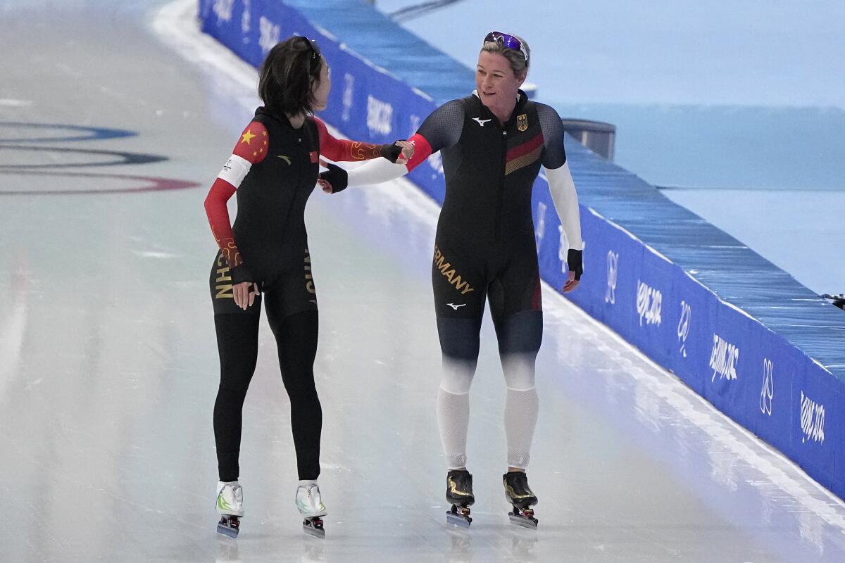 Ahenaer Adake and Claudia Pechstein skate at the 2022 Olympics.