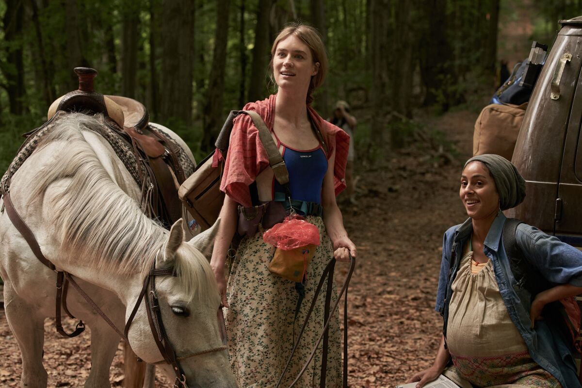 A woman with a horse and a pregnant woman squatting beside her.