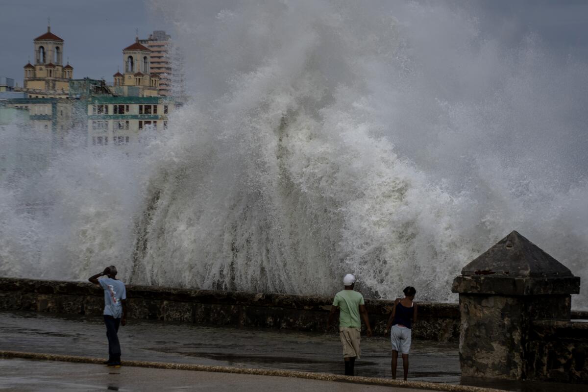 ARCHIVO - Unas personas en un muelle mientras olas enormes chocan contra el muro 