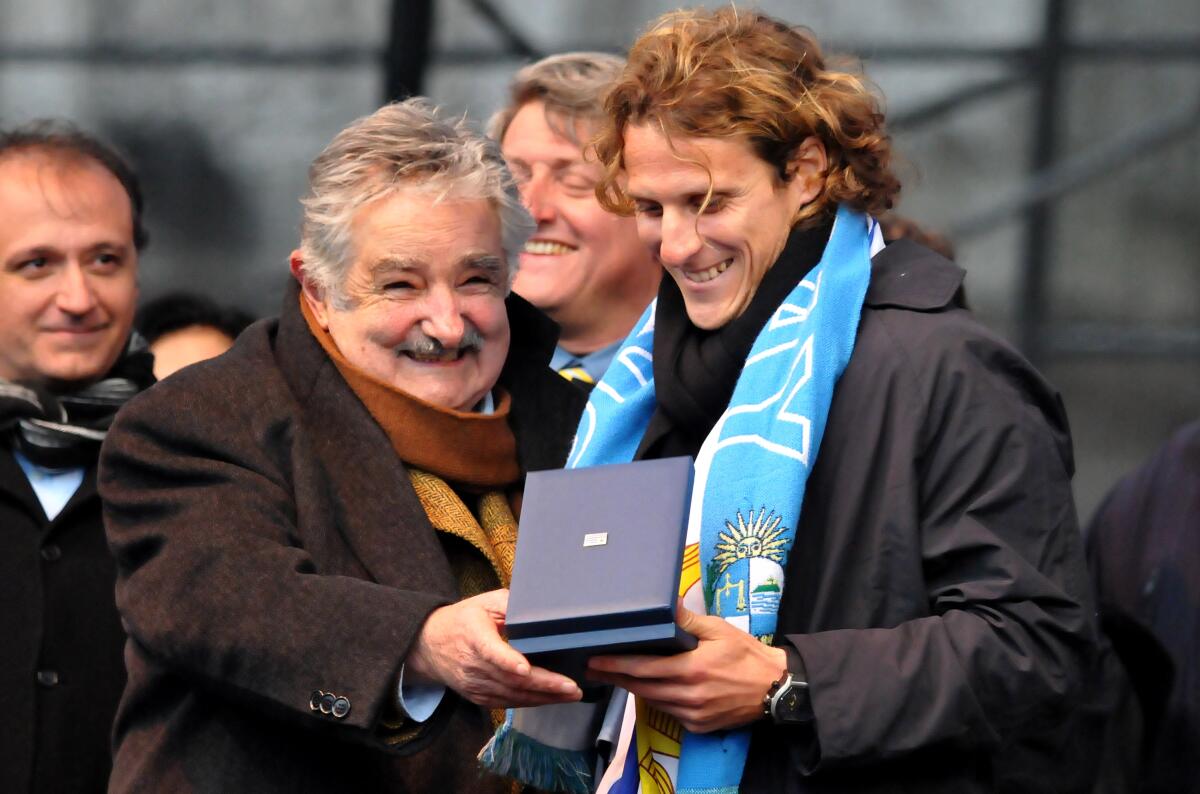 Uruguay's President Jose Mujica, left, hands a medal to Uruguay's striker Diego Forlan, to award his performance in the South Africa 2010 Soccer World Cup in Montevideo, Tuesday, July 13, 2010. Uruguay (AP Photo/Javier Calvelo)