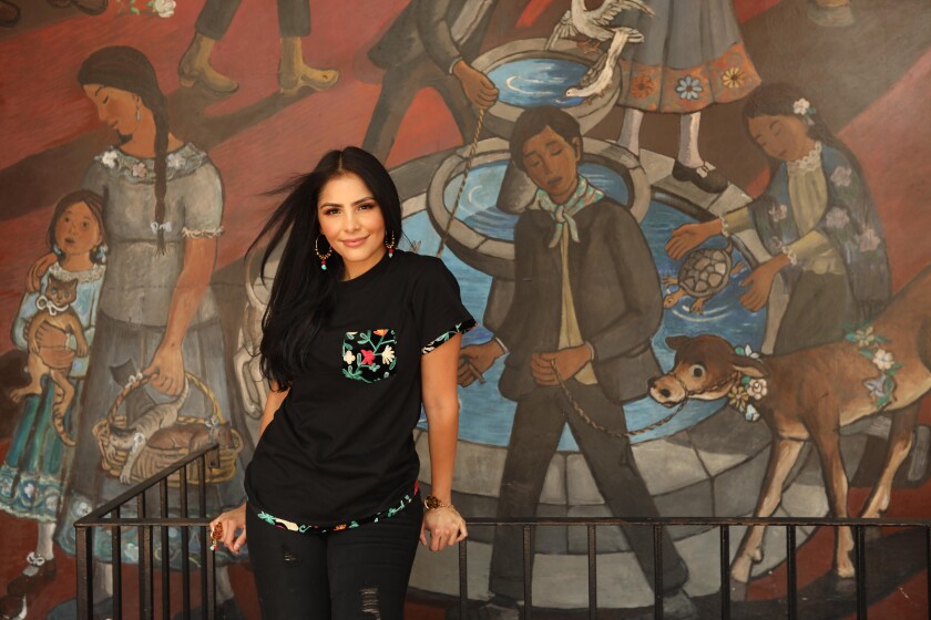 A woman stands at a railing in front of a colorful mural 