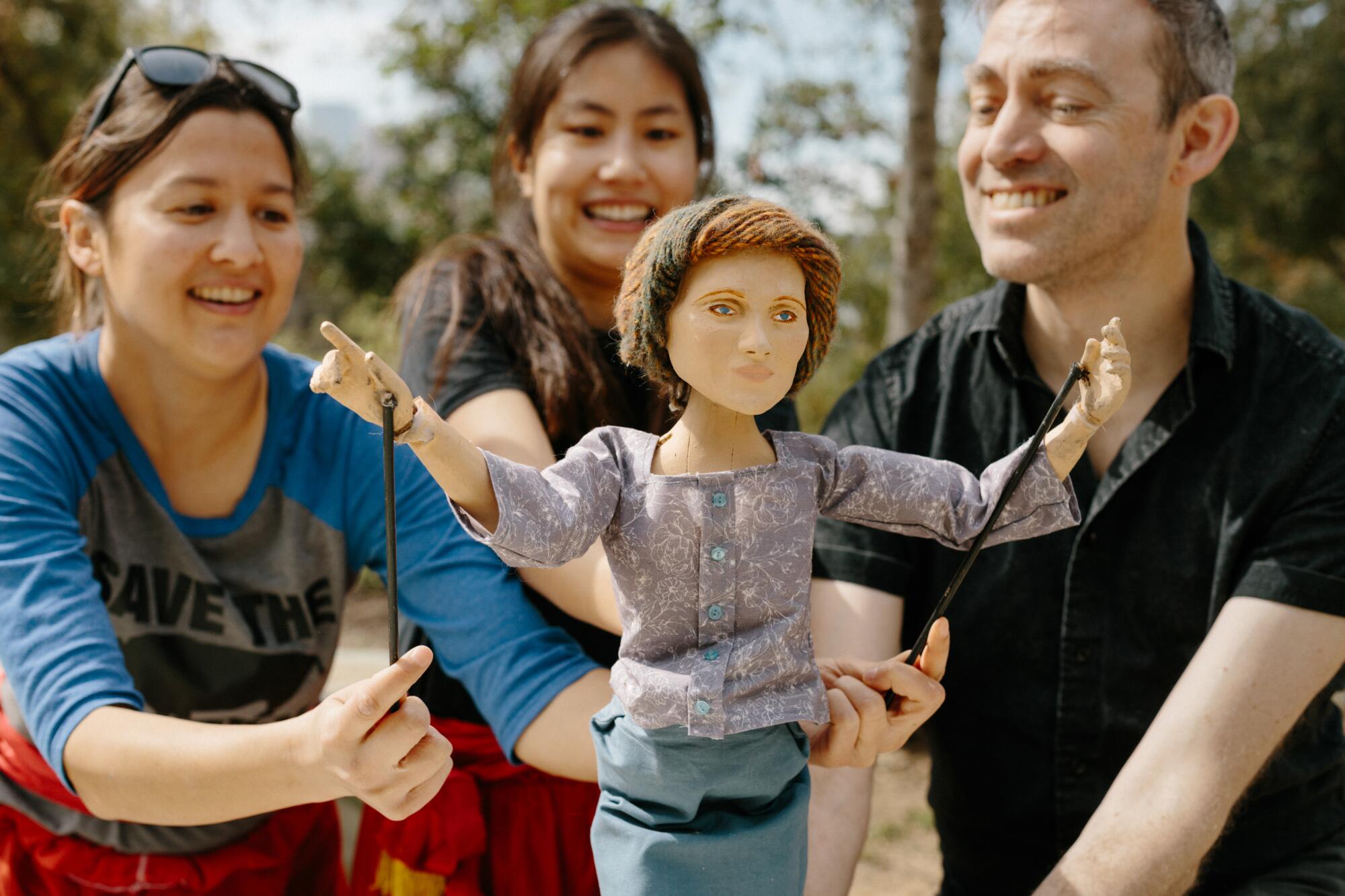 Three smiling people with a puppet.