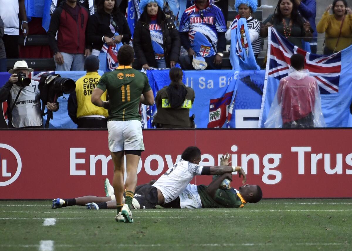 South Africa's Sakoyisa Makata scores against Fiji's Kavekini Tabu in the Rugby Sevens tournament final Sunday at Dignity Health Sports Park.