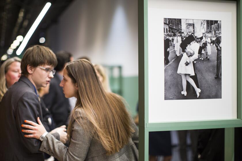 FILE - People speak next to a famous photograph taken by Alfred Eisenstaedt of a sailor kissing a nurse in New York's Times Square on V-J Day at the Jewish Museum and Tolerance Center in Moscow on April 14, 2015. Veterans Affairs Secretary Denis McDonough has reversed a department memo shared by a VA undersecretary Tuesday, March 5, 2024, that aimed to ban VA displays of the iconic photograph because it “depicts a non-consensual act” and was inconsistent with the department’s sexual harassment policy. (AP Photo/Alexander Zemlianichenko, File)