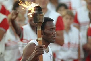 Rafer Johnson carries the Olympic torch through the Los Angeles Memorial Coliseum in 1984.