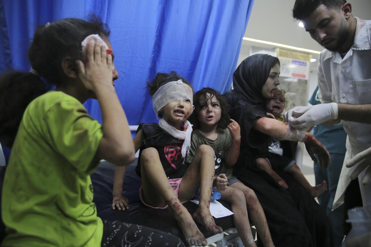 A child stanching a head injury and another with a bandaged head join others waiting to be treated by a medical worker 