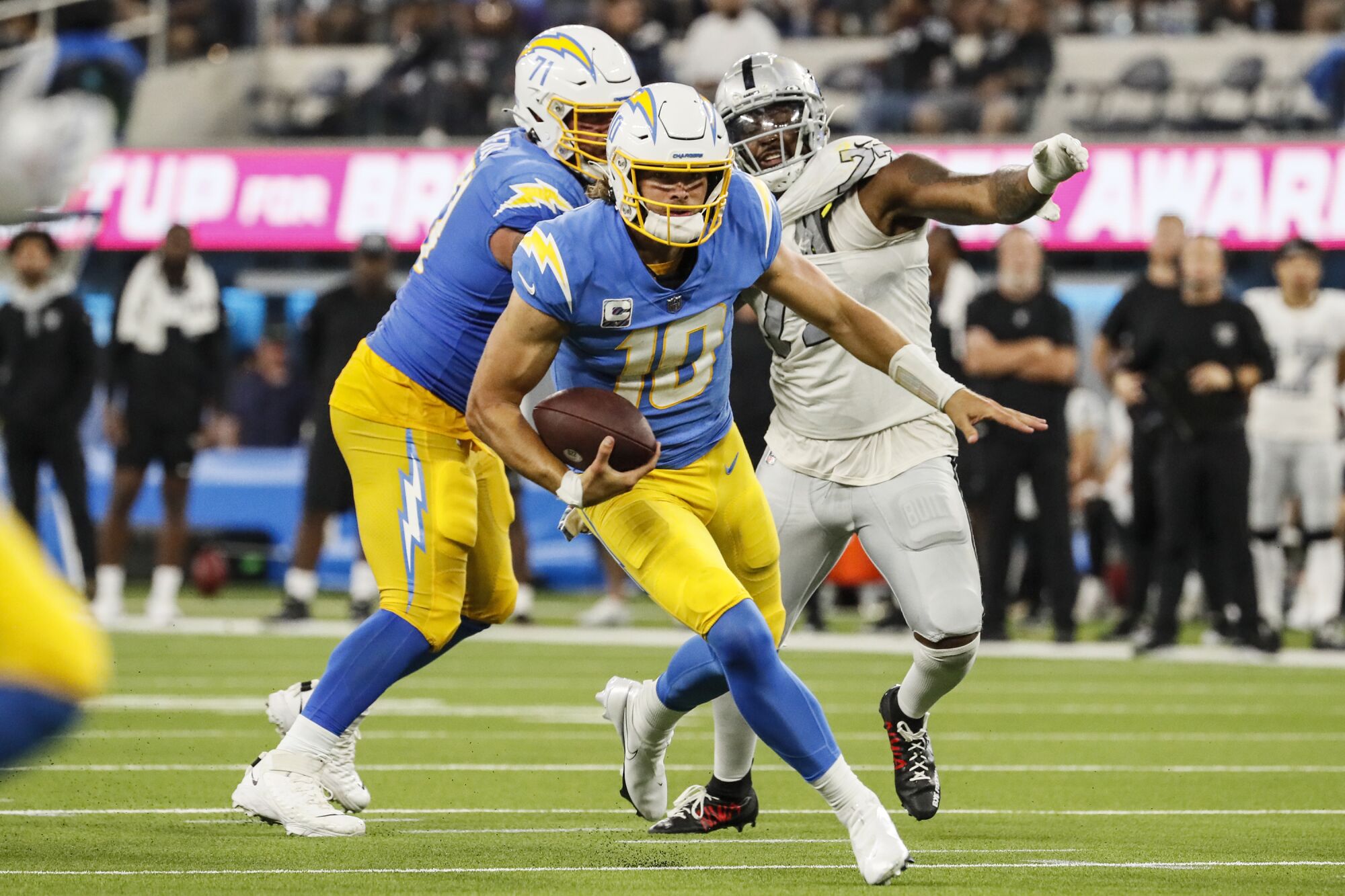 Los Angeles Chargers quarterback Justin Herbert scrambles away from Las Vegas Raiders defensive end Quinton Jefferson.