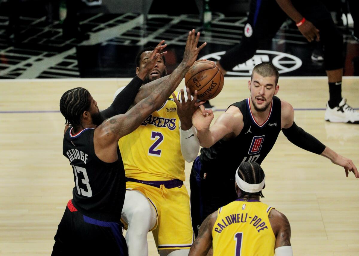 The Lakers' Andre Drummond can't grab a rebound while being double-teamed by the Clippers' Paul George and Ivica Zubac.