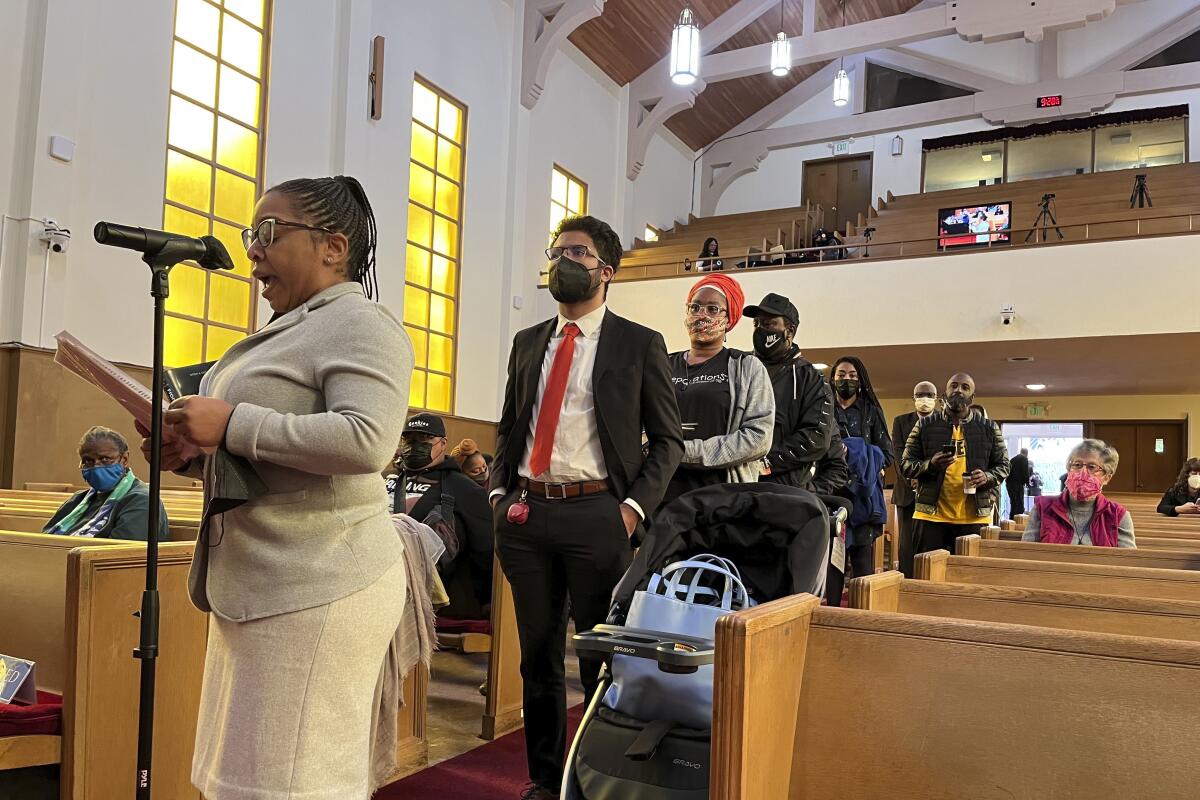 People line up between church pews to speak at a microphone