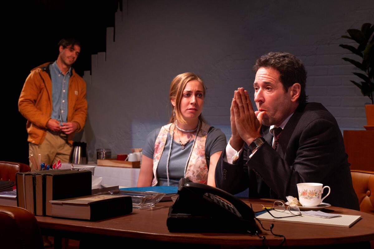 Barret T. Lewis stands looking at the seated Fiona Dorn and Rob Morrow onstage in "The Substance of Fire."