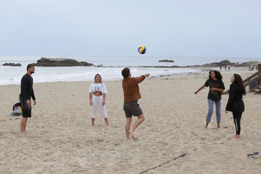 A group of friends play volleyball without a net on Main Beach, as Laguna Beach announced beach and park closures on Monday.