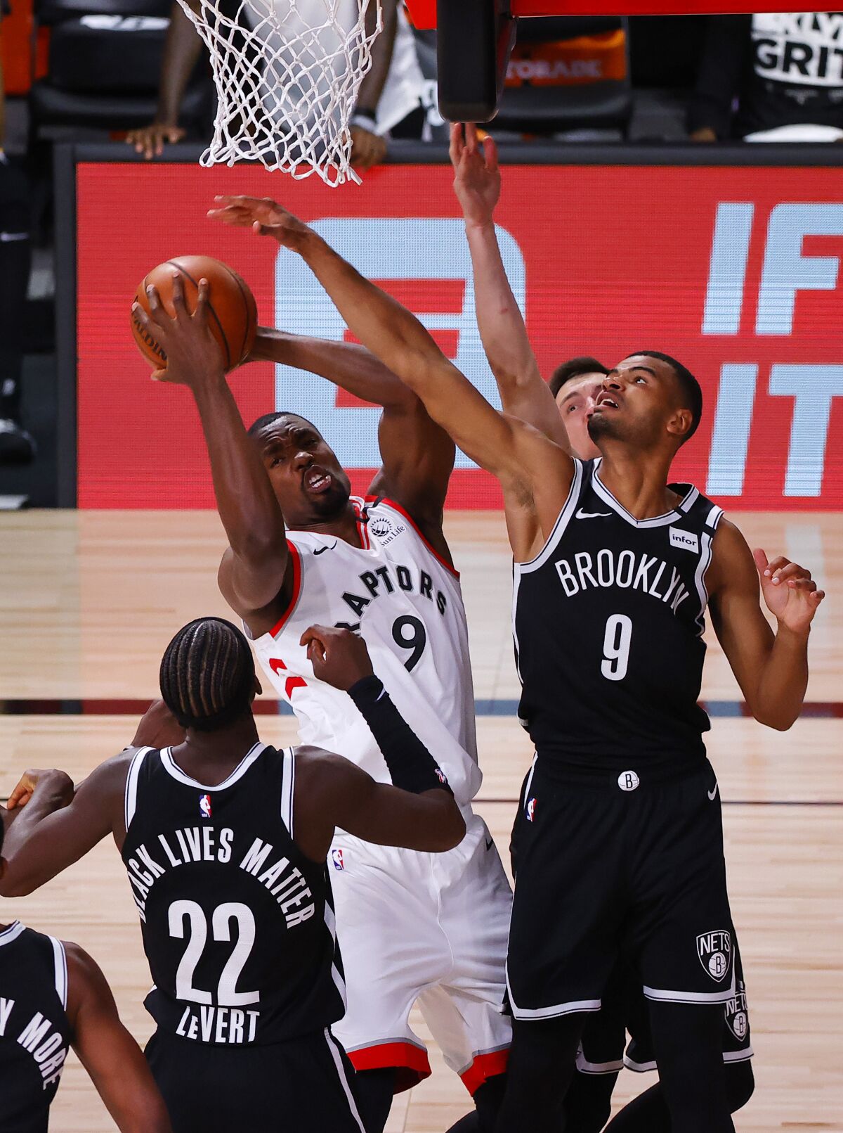 Toronto Raptors' Serge Ibaka, top left, grabs a rebound against Brooklyn Nets' Timothe Luwawu-Cabarrot, right, and Caris LeVert (22) during the third quarter of Game 1 of an NBA basketball first-round playoff series, Monday, Aug. 17, 2020, in Lake Buena Vista, Fla. (Kevin C. Cox/Pool Photo via AP)
