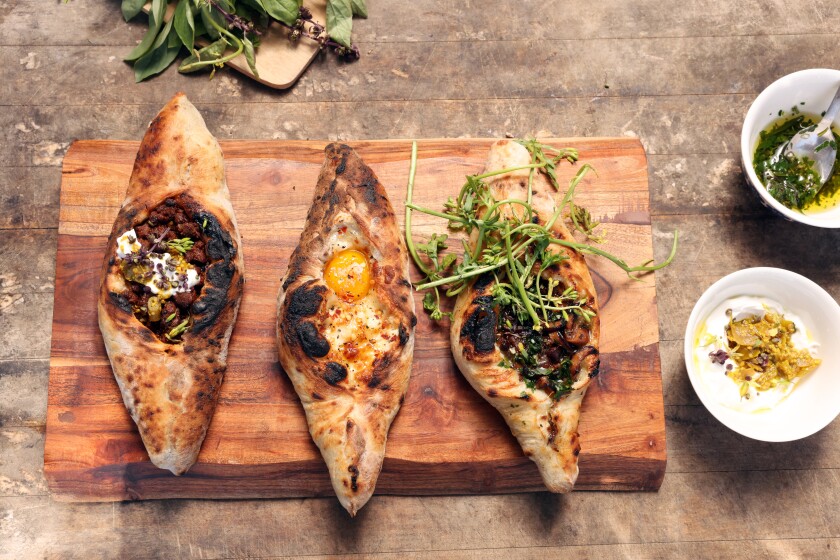 Three types of khachapuri displayed on a wooden board