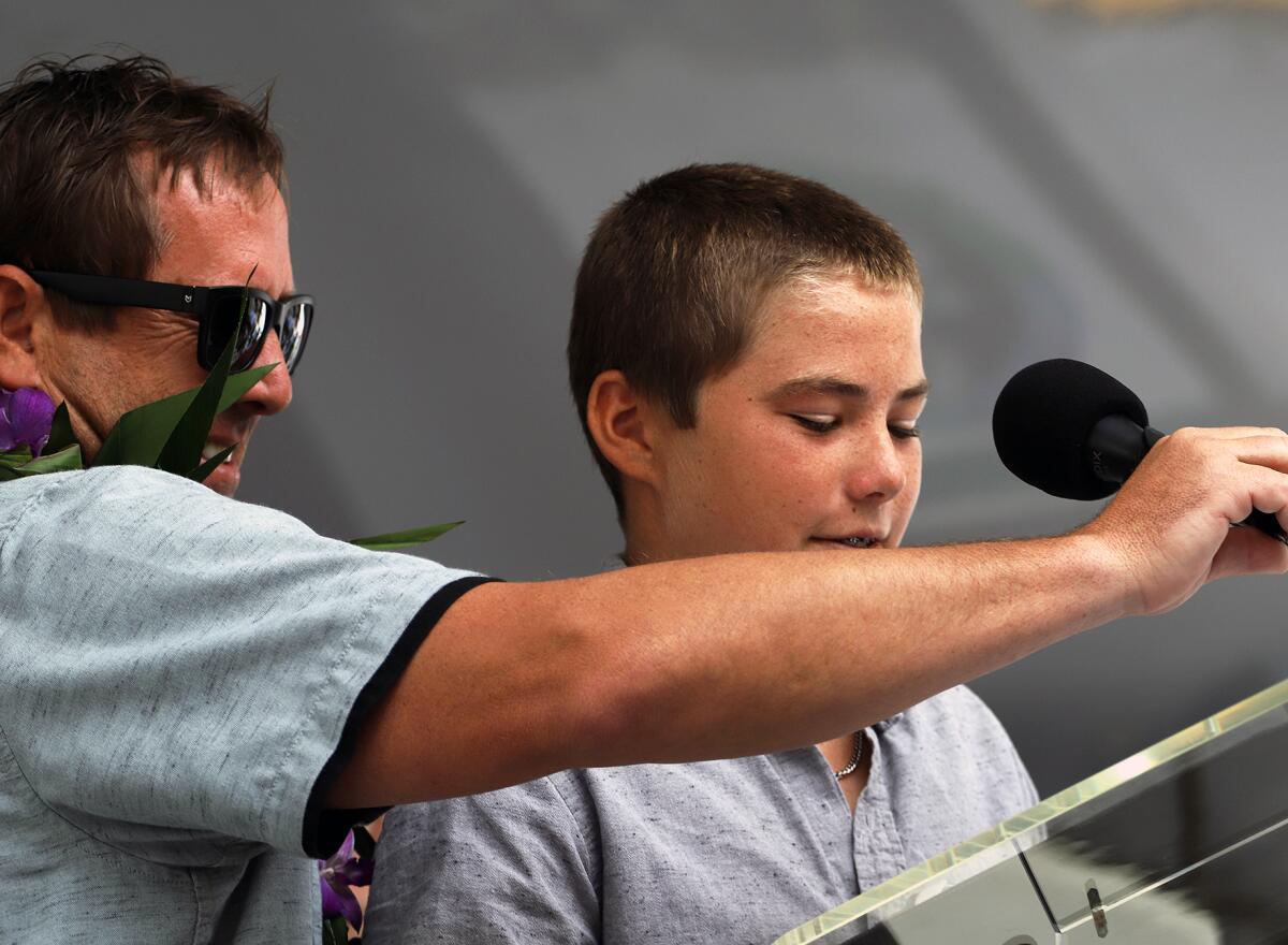 Huntington Beach local surfer Ryan Turner holds the microphone for his son Ryder as he gives his induction speech.