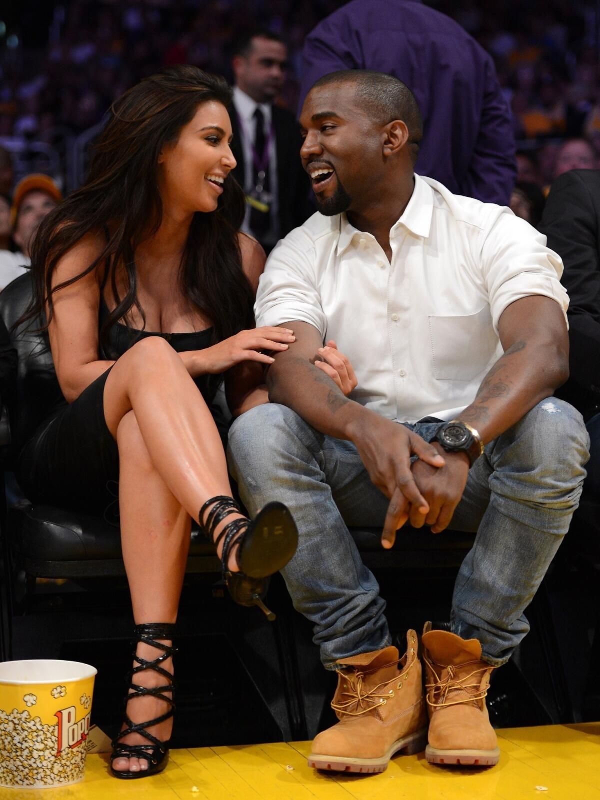 Kim Kardashian and Kanye West, sharing a laugh at a Lakers game in this file photo, are officially engaged.