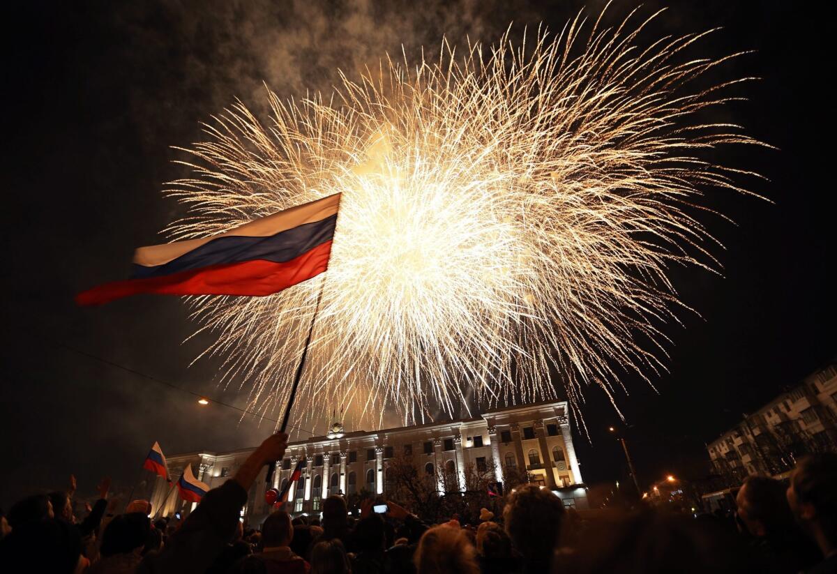 People wave Russian flags as fireworks burst above the central square in Simferopol, the capital of Crimea.