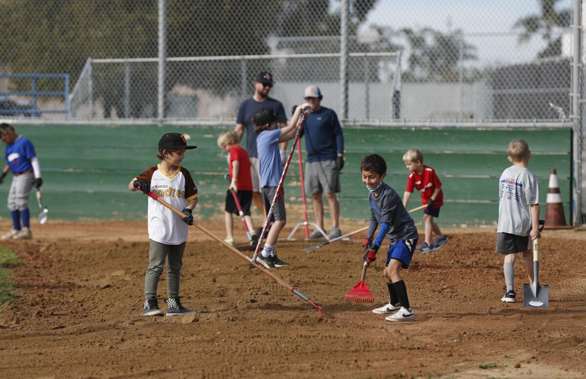 Children and parents clean up the baseball fields at Memorial Community Park in Logan Heights.