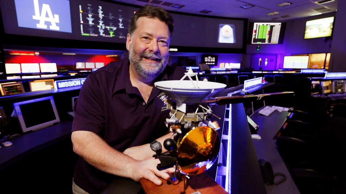 Todd Barber, Cassini's lead propulsion engineer, with a model of the spacecraft in the mission control center at JPL.