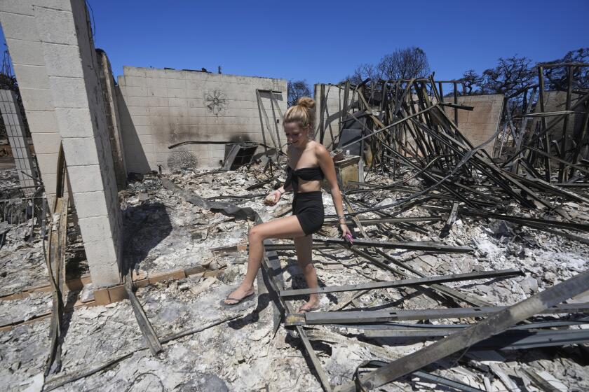 FILE - Sydney Carney walks through her home, which was destroyed by a wildfire on Aug. 11, 2023, in Lahaina, Hawaii. Lahaina residents are grappling with a range of feelings as Maui authorities plan to begin allowing them back into what has become known as the "burn zone." (AP Photo/Rick Bowmer, File)