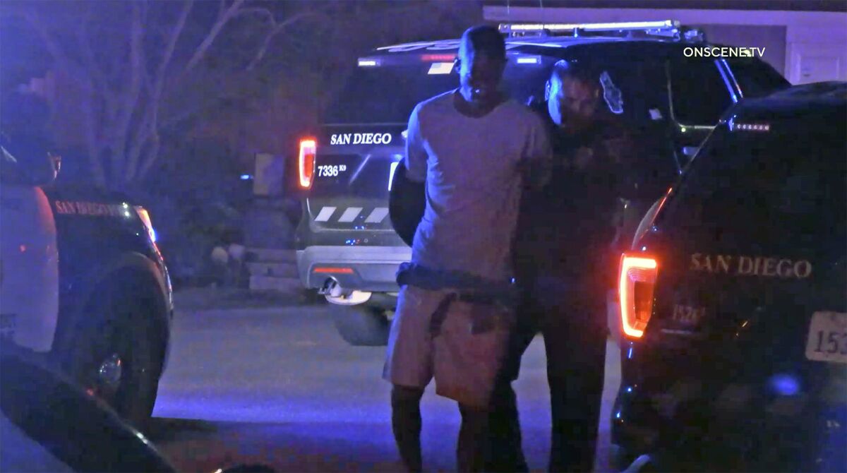 A suspect is taken into custody by police at night.