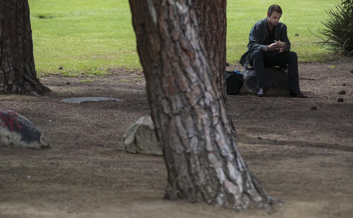 Mark Findley of Los Angeles enjoys his lunch while sitting rock among tall pines in the green space at Liberty Park in Koreatown. A private property created in 1966, for a half century the park has served as a rare reprieve in a heavily developed corridor.